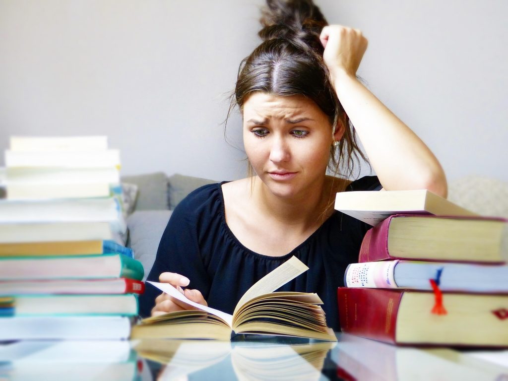 woman with books looking worried about studying